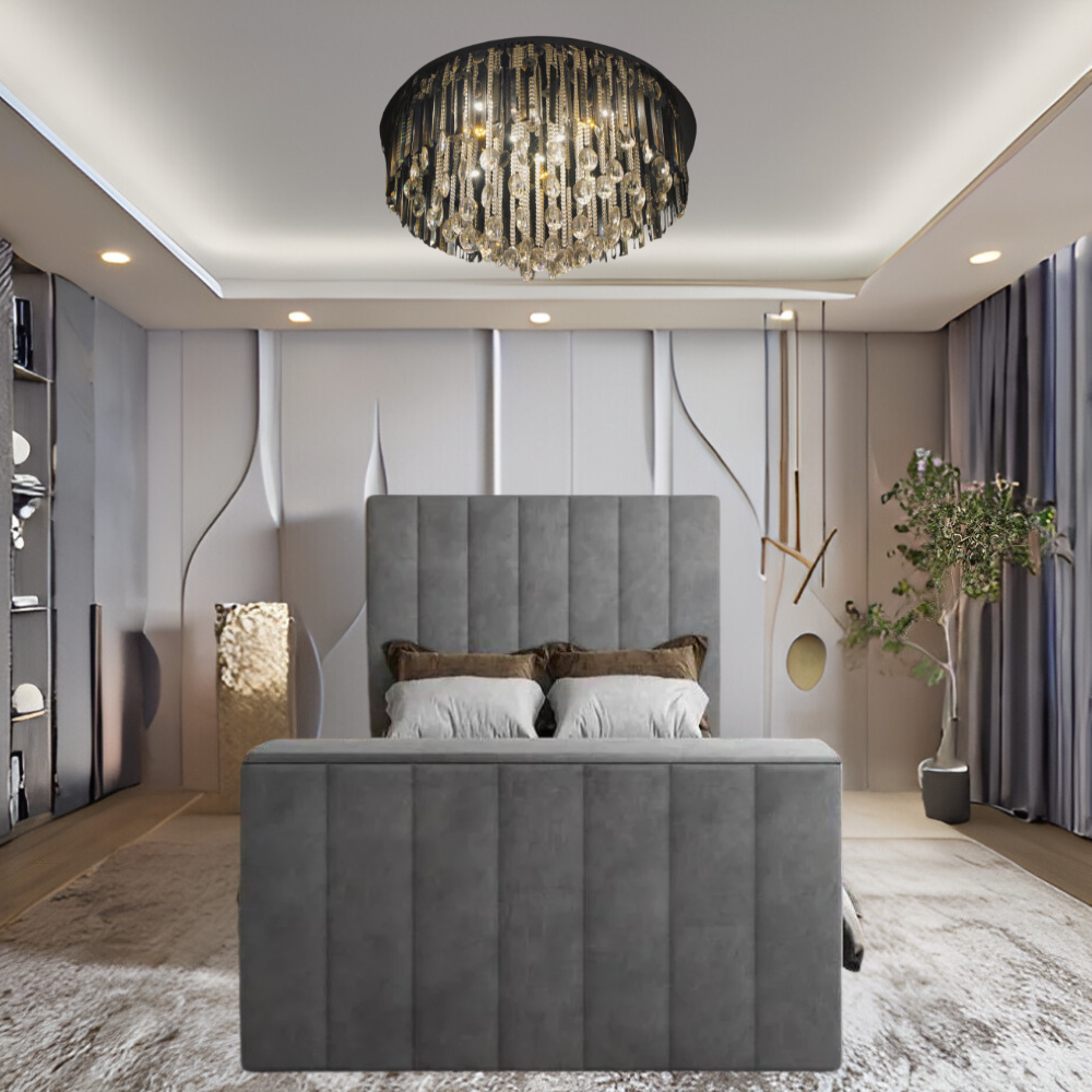 A modern bedroom with a gray upholstered bed, chandelier, decorative shelves, and a potted plant.