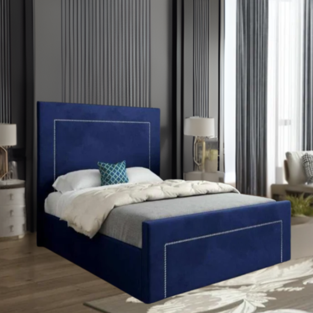A modern bedroom with a blue upholstered bed, gray walls, decorative pillow, and white nightstands.