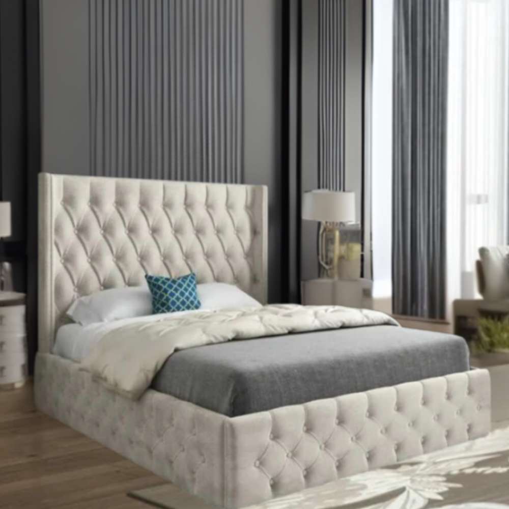 A modern bedroom featuring a large tufted bed with beige fabric, gray blanket, and teal pillow, set against dark panel walls and large window with curtains.