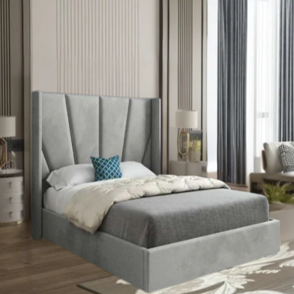 A modern bedroom with a gray upholstered bed and geometric headboard, featuring a blue decorative pillow, light gray bedspread, and cream comforter.