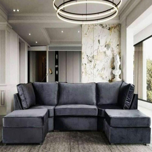 Modern living room with a dark gray sectional U Shape Elveden Sofa sofa, circular light fixture, marbled wall, and large window.