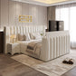 Modern bedroom with padded bed, neutral decor, and a TV at the foot of the bed.