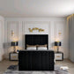 Modern bedroom with a black 2025 lily TV bed, white sheets, brown pillows, elegant lamps, and golden decor on the wall.