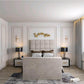 Modern bedroom with a 2025 Windsor TV bed, padded headboard, gold leaf wall art, lamps, and nightstands on a gray rug.