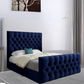 Blue tufted bed in a modern bedroom with a standing lamp and gray curtain.