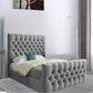 Bedroom with a grey tufted bed, blue pillow, white bedding, and a canvas art piece on the wall.