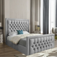 A modern bedroom with a gray upholstered tufted bed, white comforter, and blue decorative pillow.