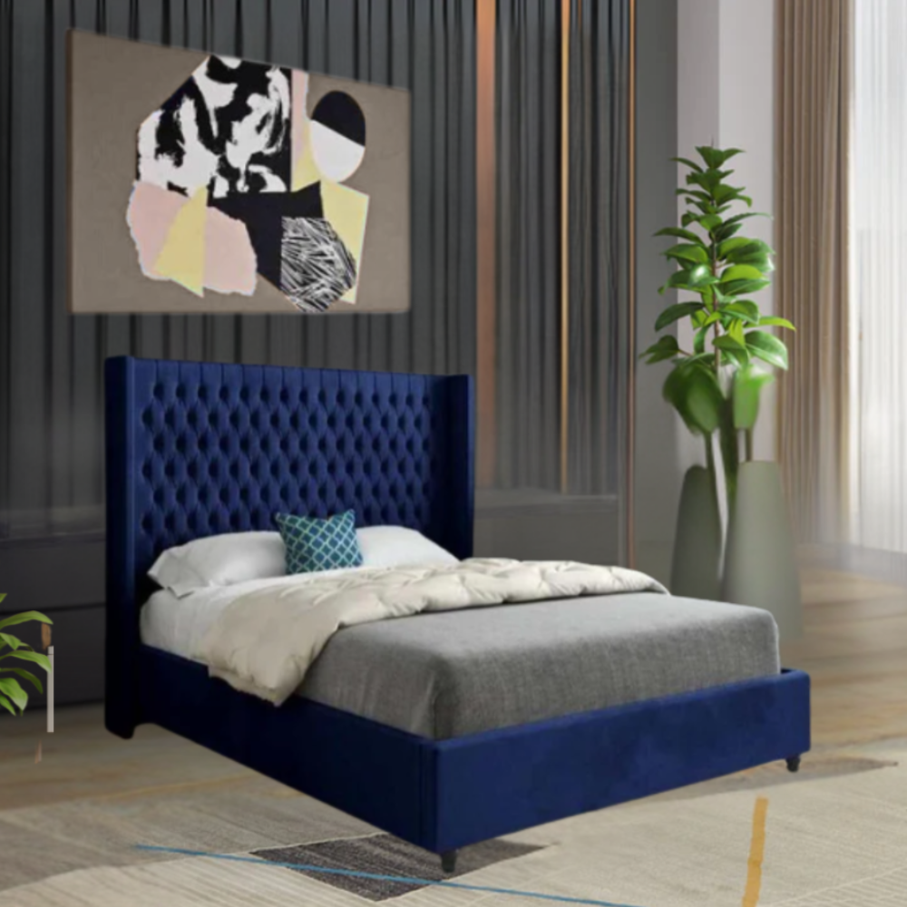 A modern bedroom with a blue tufted bed, abstract artwork above, and a tall plant to the side.